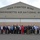 104th Fighter Wing hosts Springfield Chamber of Commerce Breakfast A large group of approximately 35-40 civilians and possibly some military personnel in civilian attire pose for a group photograph in front of a large hangar belonging to the 104th Fighter Wing, Massachusetts Air National Guard. The group appears to be participating in a community outreach, employer support, or civic leader visit event at the military installation. The setting is an outdoor tarmac area in front of the hangar's large bay doors.