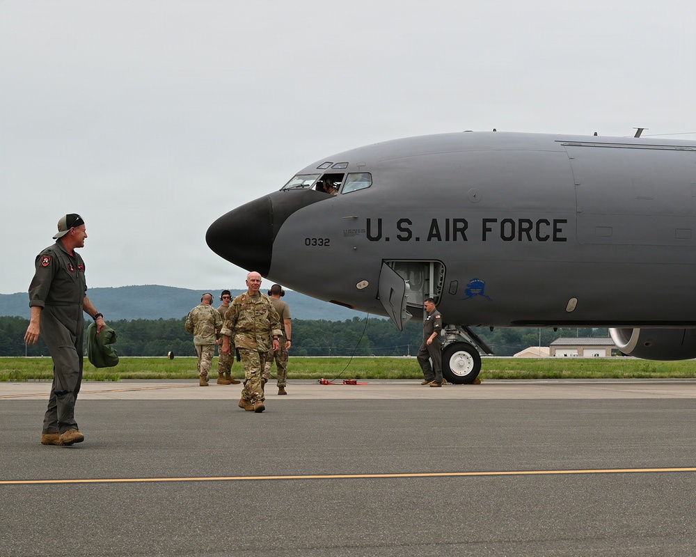 A U.S. Air Force aircraft, marked with tail number 0332, is parked on a tarmac at what appears to be a military airfield. Several personnel in military flight suits and camouflage uniforms are gathered near the nose of the aircraft. The setting appears to be a routine ground operation, possibly an arrival or pre-flight inspection.