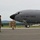 104th Fighter Wing Celebrates Flight Surgeon's Fifteen Years of Service with Fini Flight A U.S. Air Force aircraft, marked with tail number 0332, is parked on a tarmac at what appears to be a military airfield. Several personnel in military flight suits and camouflage uniforms are gathered near the nose of the aircraft. The setting appears to be a routine ground operation, possibly an arrival or pre-flight inspection.