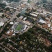 An aerial photograph of Old Dominion University's campus in Norfolk, Virginia, captured during a football game in progress at S.B. Ballard Stadium. The stadium, clearly labeled 'OLD DOMINION' and 'MONARCHS,' is filled with spectators and sits embedded within a dense urban environment. The surrounding area includes university buildings, residential neighborhoods, parking lots, and green spaces.