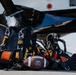 The image shows U.S. Army Golden Knights parachute rigs laid out on a tarmac surface next to an aircraft, alongside an ODU (Old Dominion University) Team Issue football. The equipment suggests a promotional or ceremonial event combining military skydiving with college football. The composition appears to be a staged publicity or pre-event photograph.