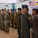 Military personnel from the United States and Brunei are standing in formation at a joint exercise called 'Pacific Angel 26-1,' a Search and Rescue Exercise (SAREX). The banner in the background displays both the American and Bruneian flags alongside the exercise name. Personnel are wearing a mix of US military camouflage uniforms and Bruneian military uniforms including flight suits and digital camouflage.
