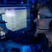 A young man wearing ESL-branded Sennheiser headphones and glasses is seated at a multi-monitor workstation in a dimly blue-lit environment. He is writing or drawing on a touchscreen monitor with a stylus while appearing to communicate via the headset microphone. The setting suggests an esports production, commentary, or analyst booth environment.