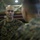 A U.S. Marine officer with the name tape 'MARTINEZ' and gold oak leaf cluster insignia (indicating the rank of Major) is engaged in conversation with other Marines in what appears to be an indoor military facility or gymnasium. He is wearing the standard Marine Corps MARPAT woodland camouflage uniform. The image captures an informal briefing or discussion among military personnel.