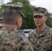 Two U.S. Marines in MARPAT (Marine Pattern) digital camouflage uniforms are engaged in a face-to-face conversation. The Marine facing the camera has a name tape reading 'TABORDA' and a 'U.S. MARINES' branch tape visible on his uniform. The setting appears to be an outdoor military area with tents and vehicles in the background.