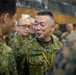The image shows a group of military personnel in what appears to be an indoor briefing or meeting environment. The central figure is wearing Japanese Ground Self-Defense Force (JGSDF) camouflage uniform with a name tape reading 'ARAI' and rank insignia visible. Personnel from what appears to be both JGSDF and U.S. Marine Corps are present, suggesting a joint military exercise or coordination event.