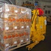 A worker wearing a blue hard hat and red shirt operates a yellow electric pallet jack/forklift inside what appears to be a large warehouse or ship cargo hold. The pallet being transported is stacked with multiple layers of cardboard boxes branded 'Thornhill Citrus,' wrapped in clear plastic stretch film. A 'CHILL' label is visible on the pallet, indicating the cargo requires refrigeration.