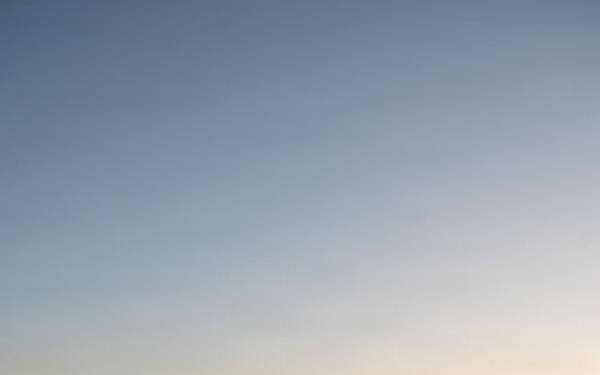 A line of U.S. Air Force military aircraft is parked on a flight line or tarmac during golden hour at sunset. The scene includes multiple aircraft types representing different mission roles, from close air support to air superiority. At least one ground crew member is visible between the aircraft.