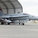 A U.S. Marine Corps F/A-18 Hornet fighter jet assigned to VMFA-232 'Red Devils' squadron, marked with tail number 07, is positioned on a flight line apron in front of a BigTop fabric hangar structure. The aircraft displays 'RED DEVILS' markings on its external fuel/drop tanks and 'VMFA-232' on the fuselage. A ground crew member is visible to the right, appearing to signal or direct the aircraft.