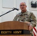 A U.S. Army soldier with the name tape 'ROGERS' is speaking at a podium labeled 'Eighth Army' during an official military ceremony or event. He is wearing MultiCam (OCP) combat uniform with U.S. Army insignia and what appears to be an Eighth Army patch on his right shoulder. The South Korean and American flags are visible in the background, indicating this event likely takes place in South Korea.
