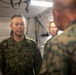 The image shows military personnel inside a tent or temporary command structure, appearing to be engaged in a briefing or discussion. At least two individuals are wearing Japanese Ground Self-Defense Force (JGSDF) camouflage uniforms, while a third person in the foreground (seen from behind) appears to be wearing US Marine Corps MARPAT camouflage. The setting suggests a joint military exercise or coordination meeting.