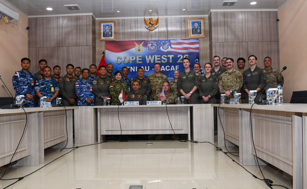 A formal group photograph of military personnel from Indonesia (TNI AU) and the United States (US PACAF) taken during the 'Cope West 26' bilateral military exercise. Personnel are posed behind a conference table in what appears to be a briefing or meeting room. The banner and table placards clearly identify the two participating nations and the exercise name.