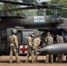 A military medical evacuation (MEDEVAC) helicopter marked 'Arctic Dustoff' is shown on the ground with personnel gathered around it. The UH-60 Black Hawk helicopter displays Red Cross markings, indicating its medical role. Several soldiers in various uniforms and flight gear appear to be loading or attending to a patient or equipment through the side door.
