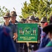 A group of men wearing traditional Alpini hats with feathers are gathered at a formal ceremony. They are displaying a green banner belonging to the 'Associazione Nazionale Alpini - Sezione di Vicenza Monte Pasubio,' decorated with medals and the ANA emblem. The event appears to be an official gathering or parade of the Italian Alpine troops veterans association.