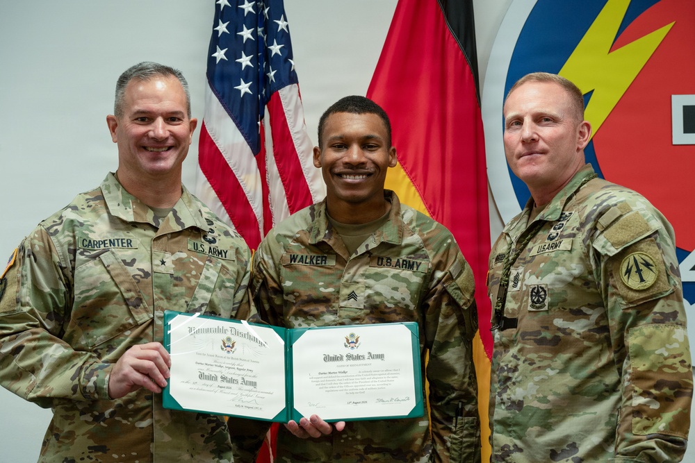 Three U.S. Army soldiers pose for a formal photo during what appears to be a military ceremony. The center soldier, identified by name tape as 'WALKER' with the rank of Sergeant, is holding an Honorable Discharge certificate from the United States Army. The soldier on the left is identified as 'CARPENTER' and wears a Brigadier General star insignia, while the soldier on the right appears to be a senior NCO.