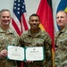Three U.S. Army soldiers pose for a formal photo during what appears to be a military ceremony. The center soldier, identified by name tape as 'WALKER' with the rank of Sergeant, is holding an Honorable Discharge certificate from the United States Army. The soldier on the left is identified as 'CARPENTER' and wears a Brigadier General star insignia, while the soldier on the right appears to be a senior NCO.