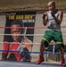 A tattooed male boxer is training in a boxing ring, shown in a fighting stance with hand wraps on both fists. Behind him is a large promotional banner reading 'Grady "The Bad Boy" Brewer' featuring a close-up portrait of a boxer wearing Everlast gloves. The setting appears to be an indoor boxing gym with an American flag visible on the wall.