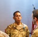 A U.S. Army Sergeant named Arroyo stands at attention during what appears to be a military awards ceremony. He is wearing an Army Combat Uniform (ACU) in OCP (Operational Camouflage Pattern) and has a medal pinned to his chest. Several other soldiers are present, and an American flag is visible in the background.