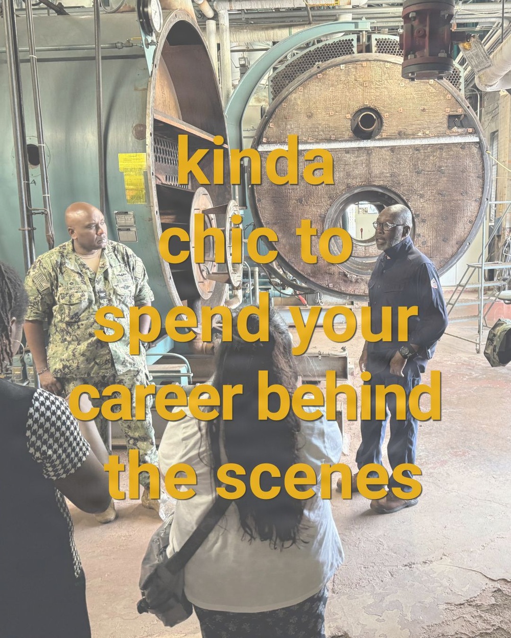 A group of people are touring an industrial facility, likely a military or government installation. A person in U.S. Navy camouflage uniform (name tag reads 'DAWSON') and a civilian in blue coveralls appear to be conducting a briefing or tour near large industrial machinery. Overlaid text reads 'kinda chic to spend your career behind the scenes.'