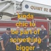 A group of seven firefighters in navy blue uniforms pose together in front of a red Pierce fire apparatus labeled 'Quint 52'. The image includes overlaid yellow text reading 'kinda chic to be part of something bigger'. The photo appears to be a team or crew photo, likely taken at a fire station.