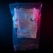 A sealed medical fluid transfer set manufactured by B. Braun is photographed against a dark background with dramatic blue and red lighting. The package contains tubing with two nonvented spikes designed for direct transfer of fluids between large volume parenteral solution containers. The product is still in its original sterile packaging with visible labeling including lot number, date, and usage instructions.