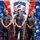 Golden Knights Defend Canopy Formation Title at Perris Three individuals wearing matching U.S. Army uniforms pose together in front of a sponsor backdrop at the 2026 USA National Skydiving Championships. Their shirts identify them as members of the Golden Knights Parachute Team. The event is sponsored by Pinkham & Associates (Orange County Divorce Attorneys APLC) and Skydive Perris (celebrating 50 years), among others.