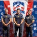 Three individuals wearing matching U.S. Army uniforms pose together in front of a sponsor backdrop at the 2026 USA National Skydiving Championships. Their shirts identify them as members of the Golden Knights Parachute Team. The event is sponsored by Pinkham &amp; Associates (Orange County Divorce Attorneys APLC) and Skydive Perris (celebrating 50 years), among others.