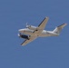 A U.S. Marines twin-turboprop aircraft is photographed in flight against a clear blue sky. The aircraft appears to be a UC-35 or similar Beechcraft King Air variant used by the United States Marine Corps. Both propellers are visibly spinning, indicating active flight.