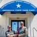 Two military personnel are posing in front of the Expeditionary Strike Group Three / Amphibious Force Third Fleet headquarters building. They are jointly holding a commemorative plaque or gift item featuring small flags, including what appear to be South Korean and American flags. The scene depicts a formal bilateral military exchange or visit between a Republic of Korea (ROK) military officer and a U.S. Navy officer.
