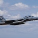A twin-engine fighter jet, identifiable as an F-15 Eagle variant, is captured in level flight against a partly cloudy sky. The aircraft appears to be in a gray paint scheme with visible tail markings and is carrying external stores/weapons. The image is well-composed and sharp, suggesting a professional or military photography context.