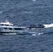 An aerial photograph shows two vessels at sea: a white and blue civilian-style motor yacht named 'Don Rulo' with registration number PC.04.00875, being approached by a rigid inflatable boat (RIB) carrying multiple personnel in dark tactical gear. The RIB appears to be conducting an intercept or boarding operation alongside the larger vessel. The scene is consistent with a maritime law enforcement or interdiction operation.