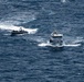 An aerial photograph shows two vessels on open ocean waters. A white civilian motor yacht named 'Don Rufo' is being approached or intercepted by a rigid inflatable boat (RIB) carrying multiple personnel in dark clothing. The scene suggests a maritime law enforcement or interdiction operation.