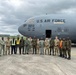 A group of approximately 18 military personnel and civilian workers pose in front of a U.S. Air Force C-17 Globemaster III aircraft on an airport tarmac. The aircraft bears tail number 0213 and is assigned to both the 437th Airlift Wing and 315th Airlift Wing. The group includes U.S. Air Force personnel in various uniforms alongside what appear to be host-nation military members in camouflage uniforms, suggesting a joint or partnership engagement.