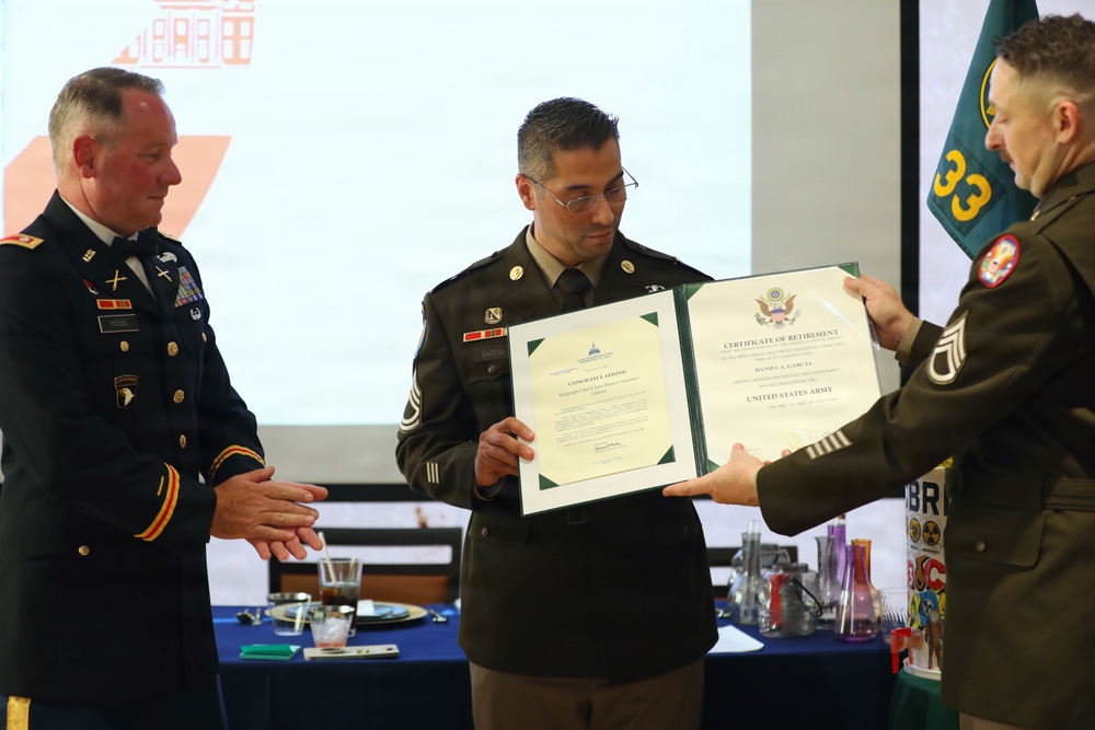 Three U.S. Army soldiers in dress uniforms are participating in a military retirement ceremony. The central figure is receiving a Certificate of Retirement from the United States Army, with the name 'Daniel A. Garcia' visible on the document. The event appears to be held in a banquet or conference room setting.
