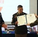 Three U.S. Army soldiers in dress uniforms are participating in a military retirement ceremony. The central figure is receiving a Certificate of Retirement from the United States Army, with the name 'Daniel A. Garcia' visible on the document. The event appears to be held in a banquet or conference room setting.