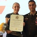 A U.S. Army soldier in dress uniform stands alongside a woman holding a Certificate of Appreciation and yellow flowers. The certificate is issued by the United States Army to Victoria R. Ramagegarcia on the occasion of her spouse's retirement. The setting appears to be a formal military retirement ceremony.