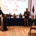 A formal military dining out ceremony for the 33rd WMD-CST (Weapons of Mass Destruction - Civil Support Team) is taking place in 2026. A senior non-commissioned officer, identifiable as a Sergeant Major by rank insignia, is speaking at a podium while another soldier stands at attention nearby. Military personnel in dress uniforms and civilian guests are seated at a head table beneath a presentation screen.