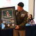A U.S. Army soldier in dress uniform is holding a framed shadow box award at what appears to be a military ceremony or retirement event. The framed plaque bears the U.S. Army seal and reads '33rd Civil Support Team (WMD)' with the name 'SFC Daniel Billingsley' on the nameplate. Attendees are applauding in the background, and a unit guidon flag with the number '33' is visible to the right.