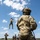 TACP students receive rappel training Military personnel are conducting rope/rappelling training in an open grassy field under a partly cloudy sky. One soldier is suspended mid-air on a red rope, while others on the ground observe, manage safety lines, or await their turn. A foreground soldier in full OCP (Operational Camouflage Pattern) uniform and tactical helmet is managing a belay rope.