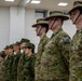 A formal military parade or ceremony featuring personnel from multiple nations standing at attention in a line inside a modern building. Australian Army soldiers wearing distinctive wide-brimmed slouch hats and MultiCam uniforms with Australian flag patches are prominently visible in the foreground, alongside Japanese Ground Self-Defense Force personnel in the middle ground. Additional military personnel in various uniforms, including what appears to be naval dress whites, are visible in the background.
