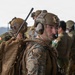 The image shows military personnel from what appears to be a joint U.S. Marine Corps and Japanese Ground Self-Defense Force exercise or operation. The foreground features a U.S. Marine wearing MARPAT camouflage, a tan tactical helmet with 'JTAC' label, communications headset, and a tactical backpack with a radio antenna. In the background, personnel in Japanese military uniforms with Japanese flag patches are visible alongside other U.S. Marines.