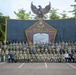 A large group of military personnel from multiple nations pose for a formal group photograph in front of the Sesko TNI (Indonesian Armed Forces Staff and Command School) monument. The backdrop features the Indonesian Garuda Pancasila national emblem atop a dark wall displaying the 'Sapta Marga' (Seven Pledges) military code of conduct. The gathering appears to be a multinational military education or cooperation event.