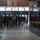 MRF-D Marines tour Melbourne Cricket Ground A group of approximately 20-25 people, predominantly young males, are gathered in what appears to be a stadium or arena lobby near Gate 2. Two individuals on the left side appear to be addressing or presenting to the group. The setting includes display cases, framed photographs on the wall, and ceremonial flags, suggesting an official tour or orientation event.