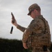 A military police soldier in OCP (Operational Camouflage Pattern) uniform is performing a magazine reload or weapons check with a pistol. The soldier has ejected or dropped a magazine while holding the pistol raised in their right hand. The image appears to be taken during a training exercise or qualification event.