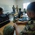 Allies, partners train together during Phoenix Express 2026 A military classroom training session showing personnel in various camouflage uniforms seated at desks with tactical equipment. Two instructors or senior personnel are standing at the front of the room near a whiteboard, appearing to conduct a briefing or instruction. Military gear including helmets, rifles, and tactical bags are visible on the desks.
