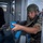 Allies, partners train together during Phoenix Express 2026 A soldier in camouflage uniform and tactical helmet is conducting what appears to be a military training exercise, aiming an AK-pattern rifle with blue training/MILES gear attachments through a doorway. The blue-colored magazine and handguard wrap indicate this is a training simulation rather than a live operation. A second figure in dark clothing is visible in the background, also appearing to participate in the exercise.