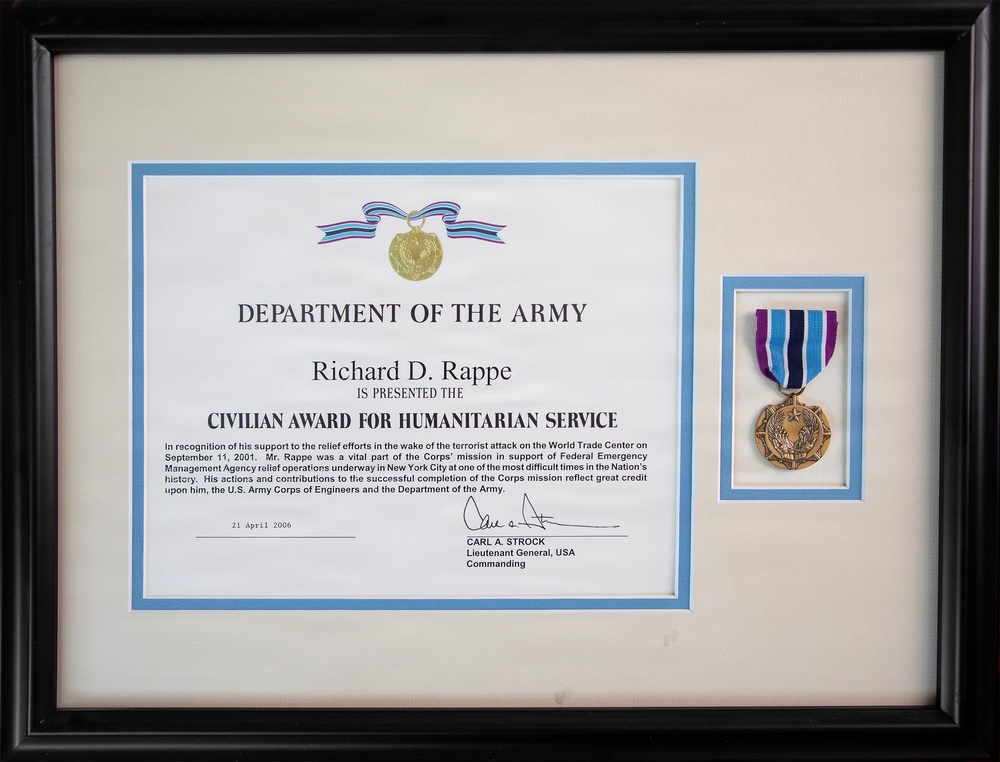 A framed Department of the Army certificate presenting the Civilian Award for Humanitarian Service to Richard D. Rappe, dated 21 April 2006. The award recognizes his support to relief efforts following the September 11, 2001 terrorist attack on the World Trade Center, specifically his role in FEMA relief operations in New York City. The framed display includes both the certificate and the physical medal mounted alongside it.