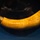The image shows an engraved animal horn, likely a powder horn or drinking horn, displayed in what appears to be a museum setting under dramatic lighting. The horn is curved and yellowish-amber in color with visible inscribed text and decorative dot patterns along its surface. The name 'JOHN' and partial additional text are legible among the engravings.