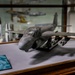 A museum display case features a scale model of a Grumman A-6A Intruder strike aircraft, mounted on a gray surface. The accompanying placard identifies it as recovered from the Pentagon Building following the crash of American Airlines Flight 77 on September 11, 2001. The model belongs to the Department of the Navy and bears catalog number 2130.