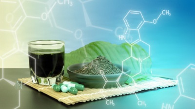 The image is a composite promotional or educational graphic combining physical objects with overlaid chemical structure diagrams. It features natural supplement products including a dark liquid in a shot glass, green powder in a bowl, capsules, and large leaves arranged on a bamboo mat. Chemical molecular structures are digitally superimposed over the background, suggesting a scientific or nutraceutical context.